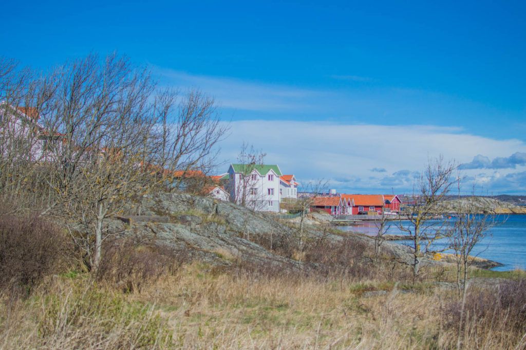 Bohuslänskt kustlandskap med klippor, sjöbodar och trähus vid vattnet.